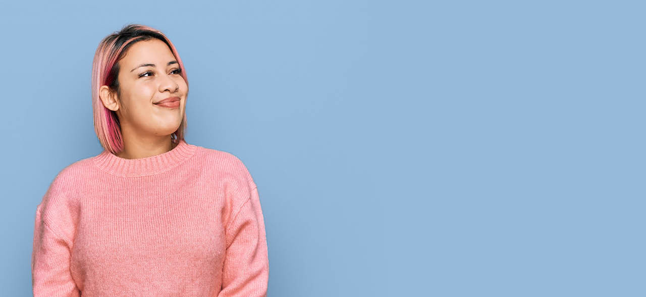eine lächelnde Frau mit rosa Haaren und einem rosa Pullover
