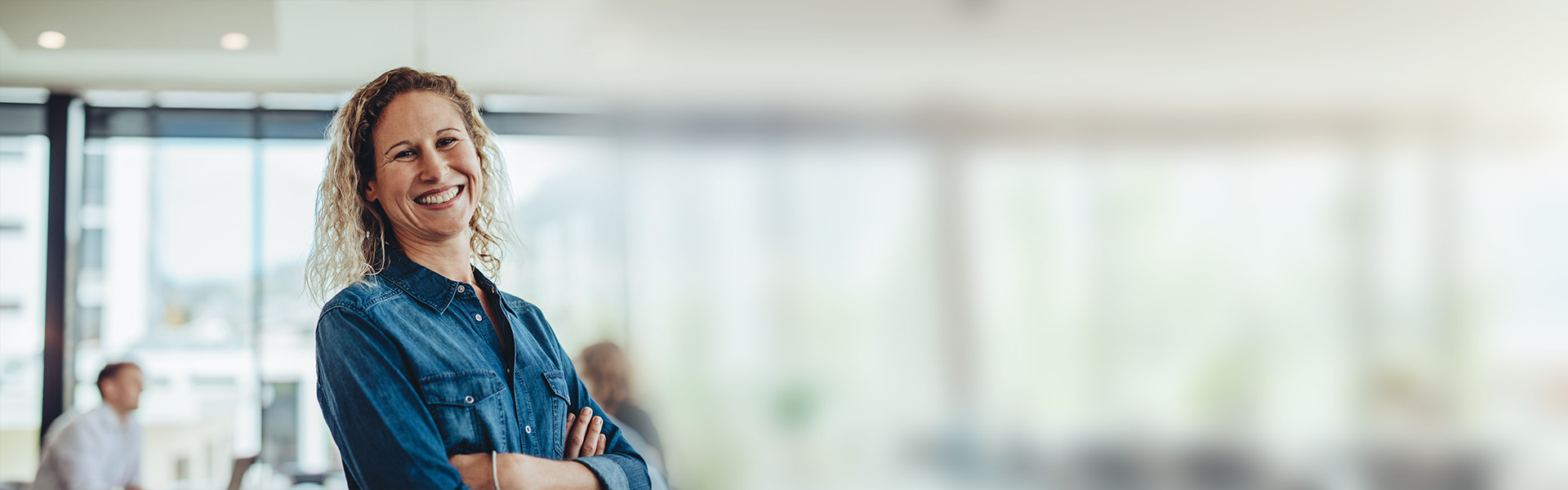 eine Frau, die mit verschränkten Armen in einem Büro steht