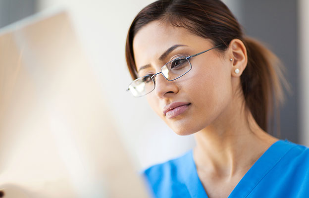 eine Frau in einem blauen Peeling Anzug und Brille Blick auf einen Computer-Bildschirm