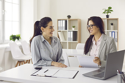 zwei Frauen sitzen an einem Tisch mit Laptops