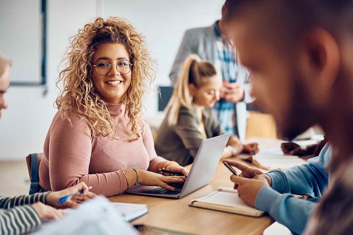 eine Gruppe von Menschen, die um einen Tisch sitzen und zwei Männer die Hände schütteln